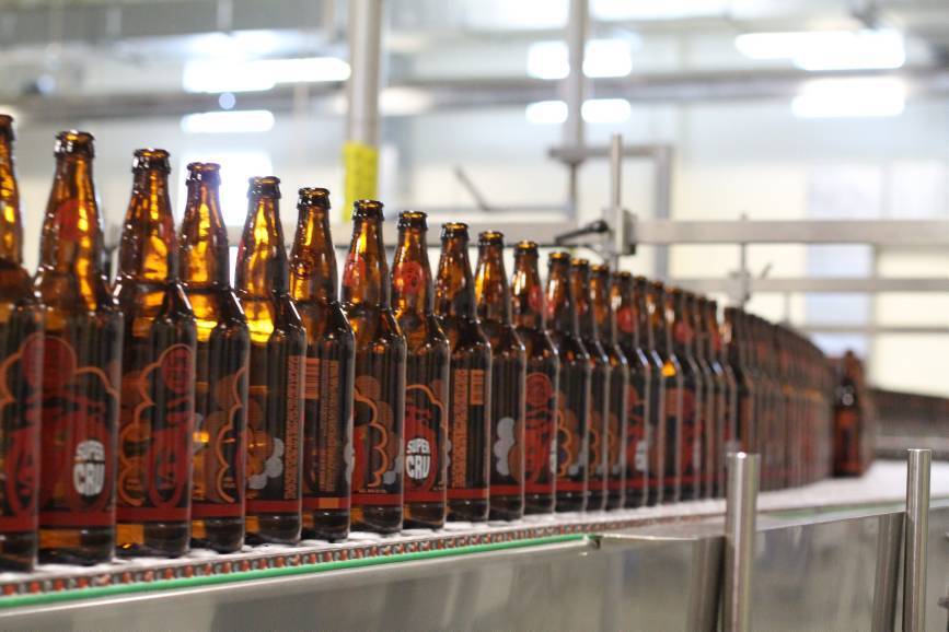 Beer bottles moving along a brewery bottling line, representing production planning software for the brewing industry.